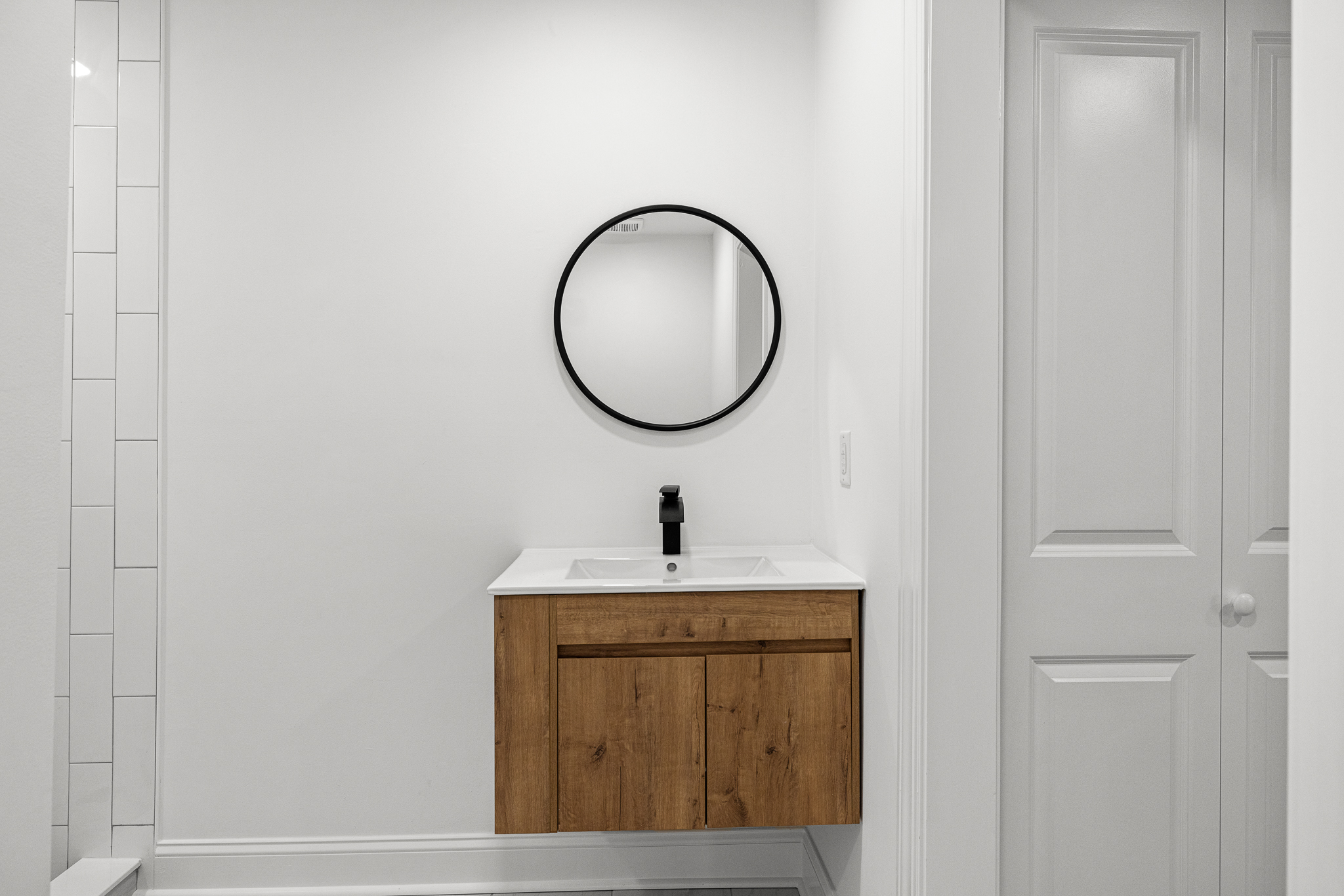 Bathroom vanity with wood finish and circular mirror